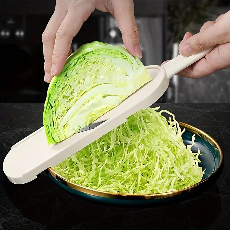 Half a cabbage being pushed across the blade onto a plate of fine shreds